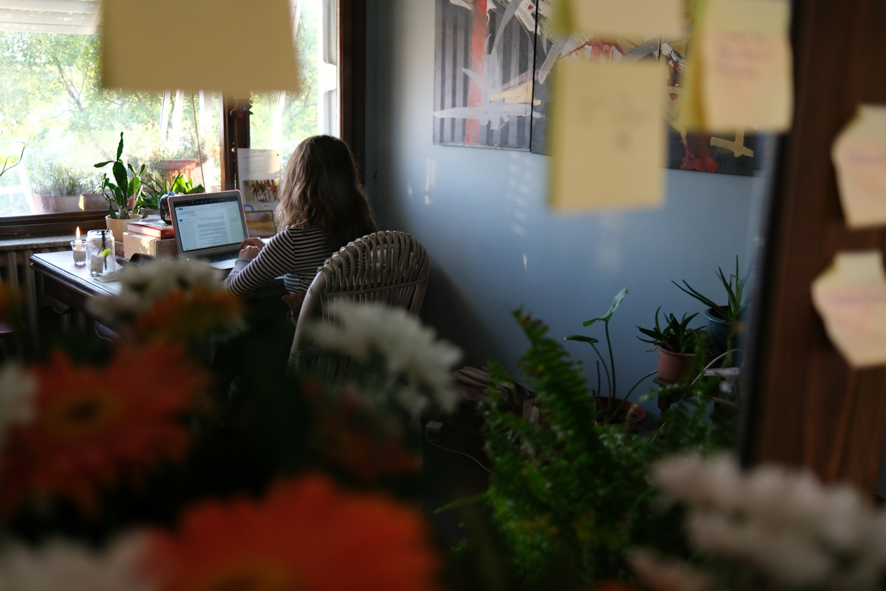 Persona trabajando de forma remota con laptop en un espacio rodeado de plantas