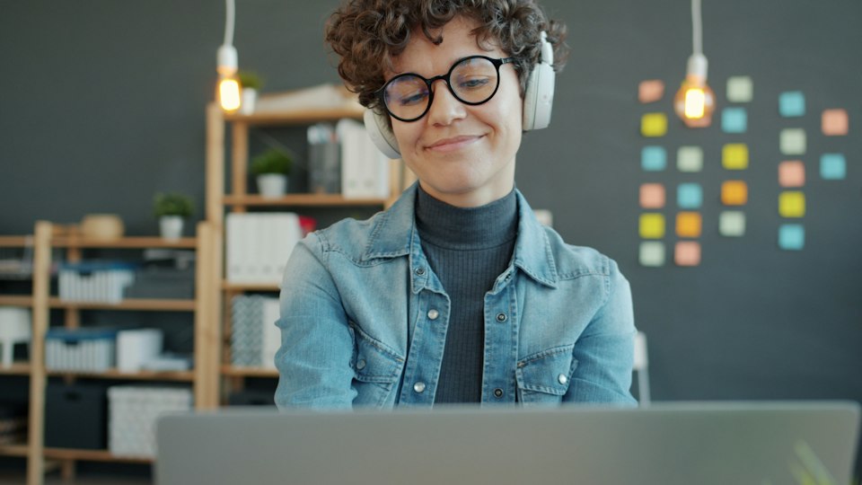 Persona con auriculares estudiando frente a un computador portátil
